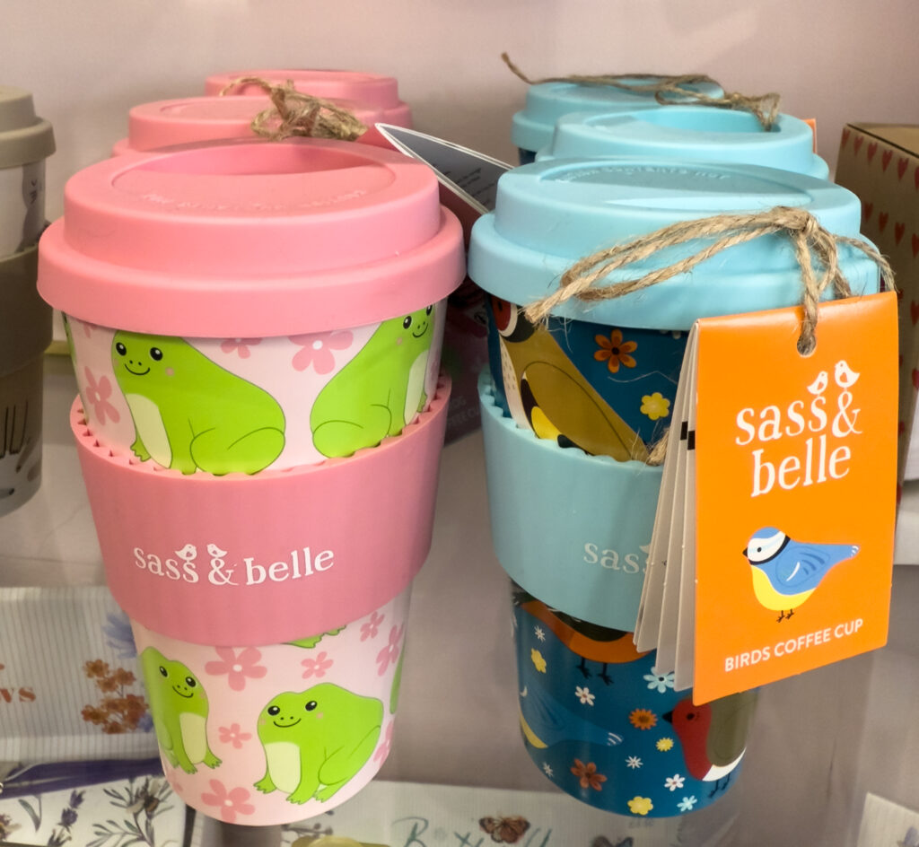 two takeaway coffee cups, one pink and one blue lids and holders.
