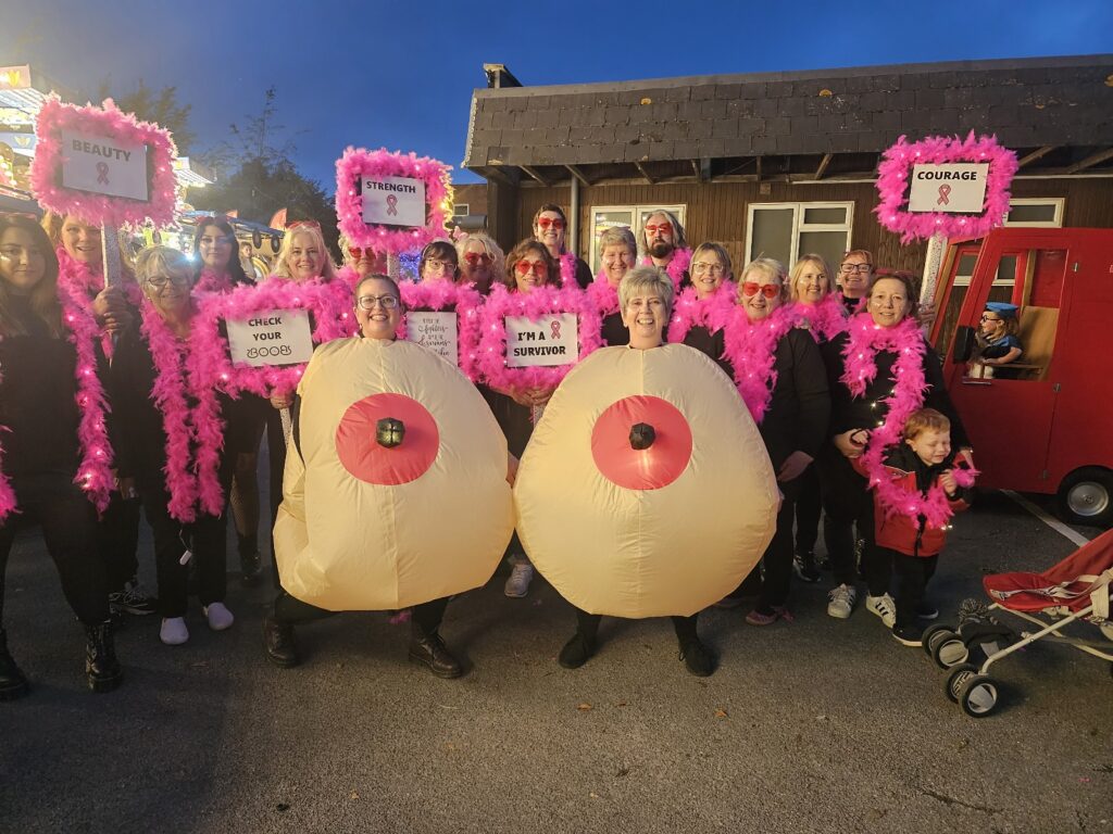 group of people holding two big inflatable breasts for a parade
