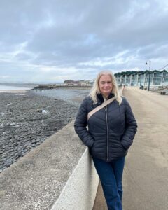 Lady standing on a sea wall, smiling