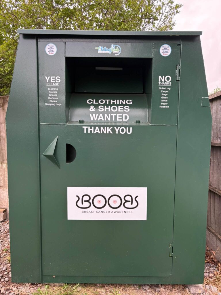 Image of a dark green, metal container, with a trap for putting donations in.